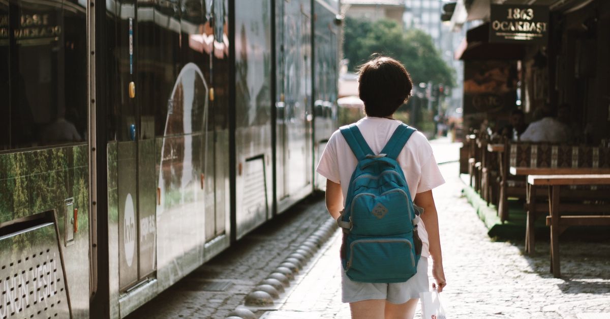 A person walking along a sunlit city pavement