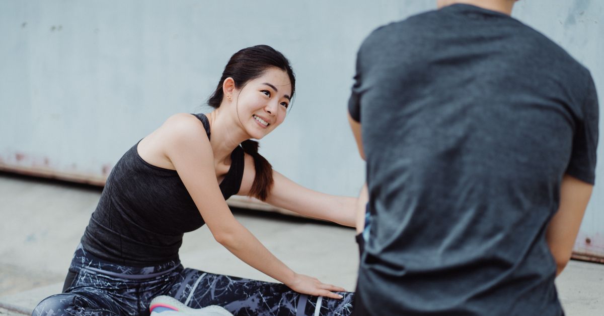 Young woman smiling while stretching outdoors during a fitness session