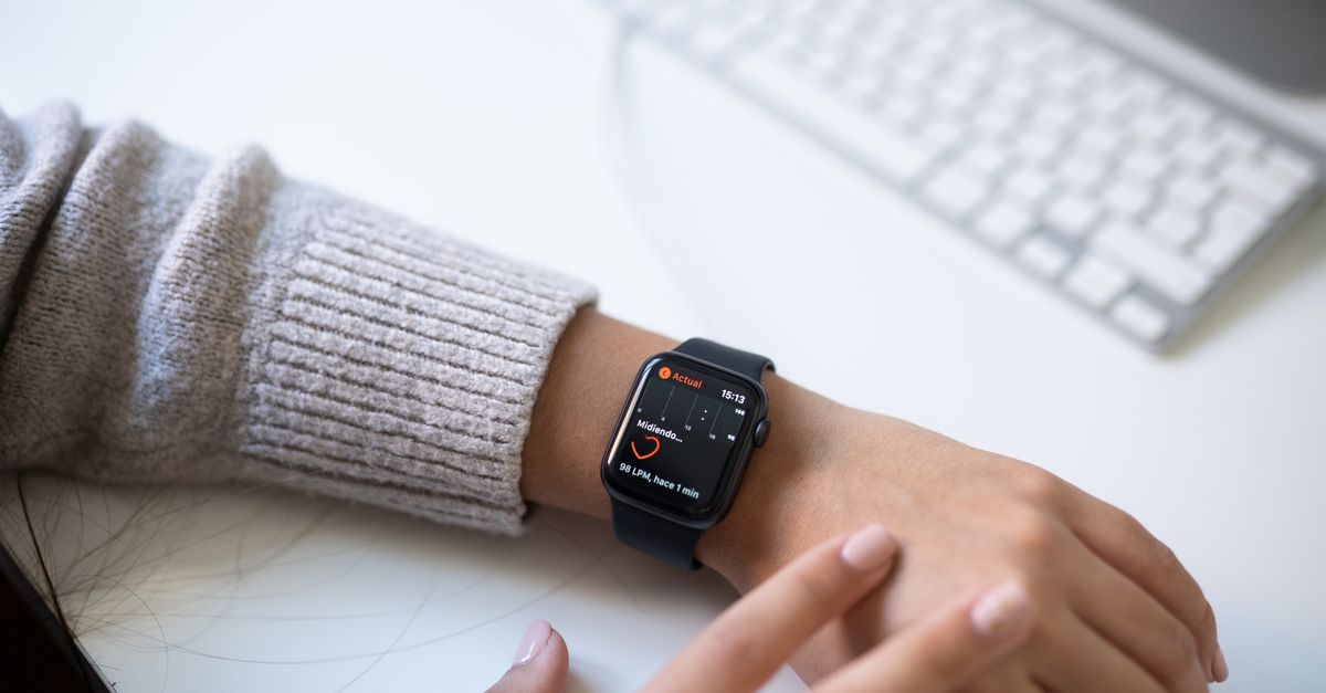 A person wearing a black smartwatch checking health data