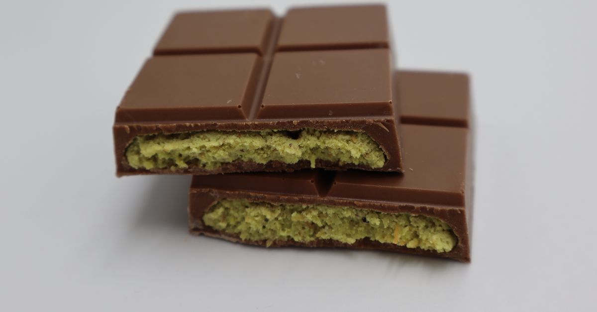 Close-up of a milk chocolate bar with pistachio filling, showcasing its delectable texture.