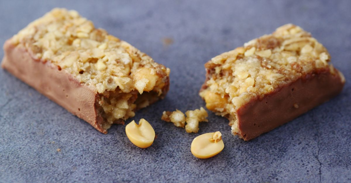 Close-up of a broken chocolate and nut energy bar on a gray surface.