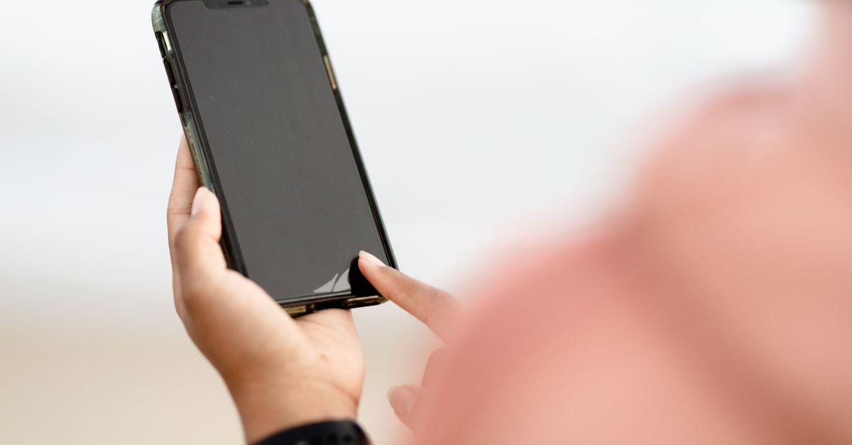 A hand interacting with a smartphone touchscreen outdoors