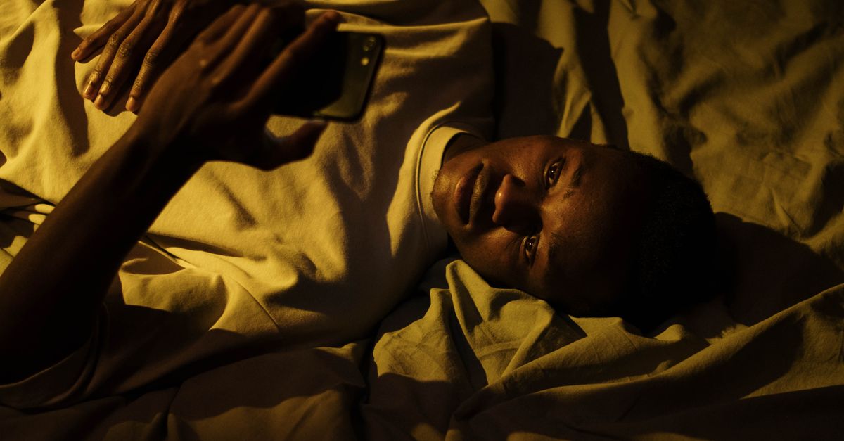 A person lying in bed using a smartphone at night