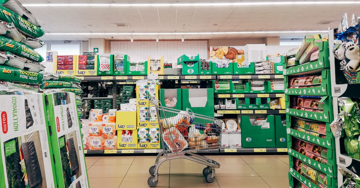 Shopping cart in a supermarket aisle stocked with packaged food
