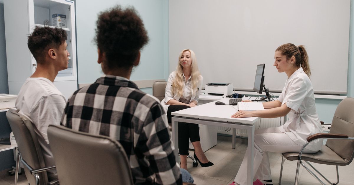 Doctors talking with patients during a medical appointment in a clinic office setting.