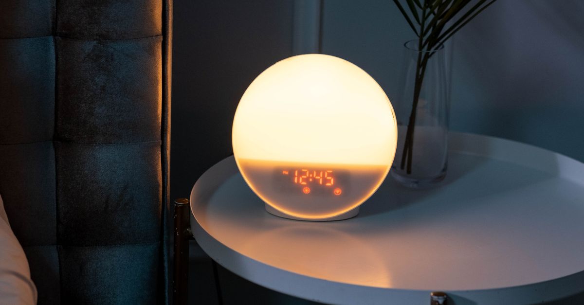 A glowing alarm clock on a bedside table at night